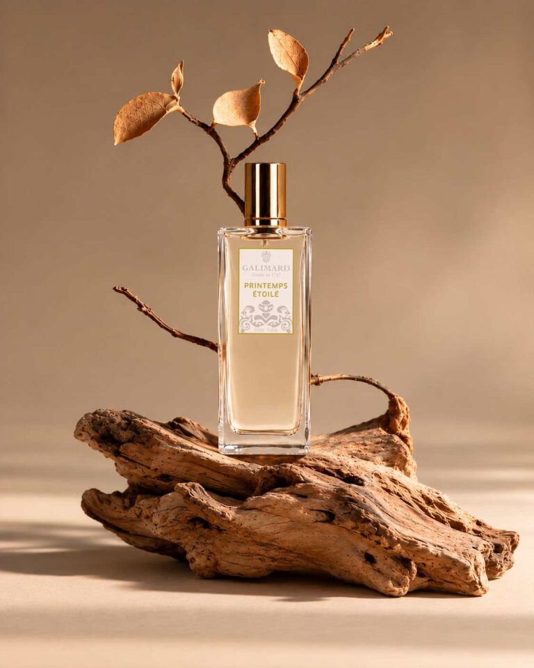Parfum Galimard Printemps Étoilé posé sur du bois naturel, entouré de branches et de feuilles aux tons automnaux.